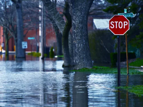 Flooded street in a community with a stop sign in the foreground.