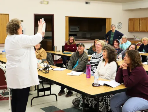 Librarians at a STEM Fair watching a presenter demonstrate a science program.