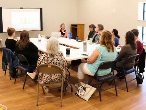 About 15 people sitting around a conference table at the 2024 Director Roundtables at the Prairie City library.