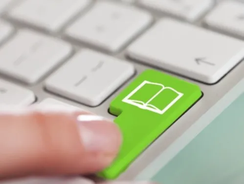 Closeup of a finger pressing a green keyboard button labeled with a book icon.