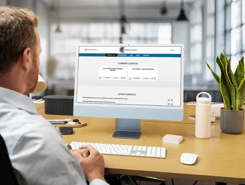 Man sitting in front of a computer open to the Annual Survey interface.