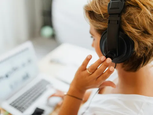 Person sitting at a laptop using over the ear headphones as an example of a screen reader user.