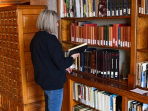 Woman selecting a book from shelves in the State Law Library.