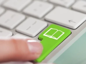 Closeup of a finger pressing a green keyboard button labeled with a book icon.