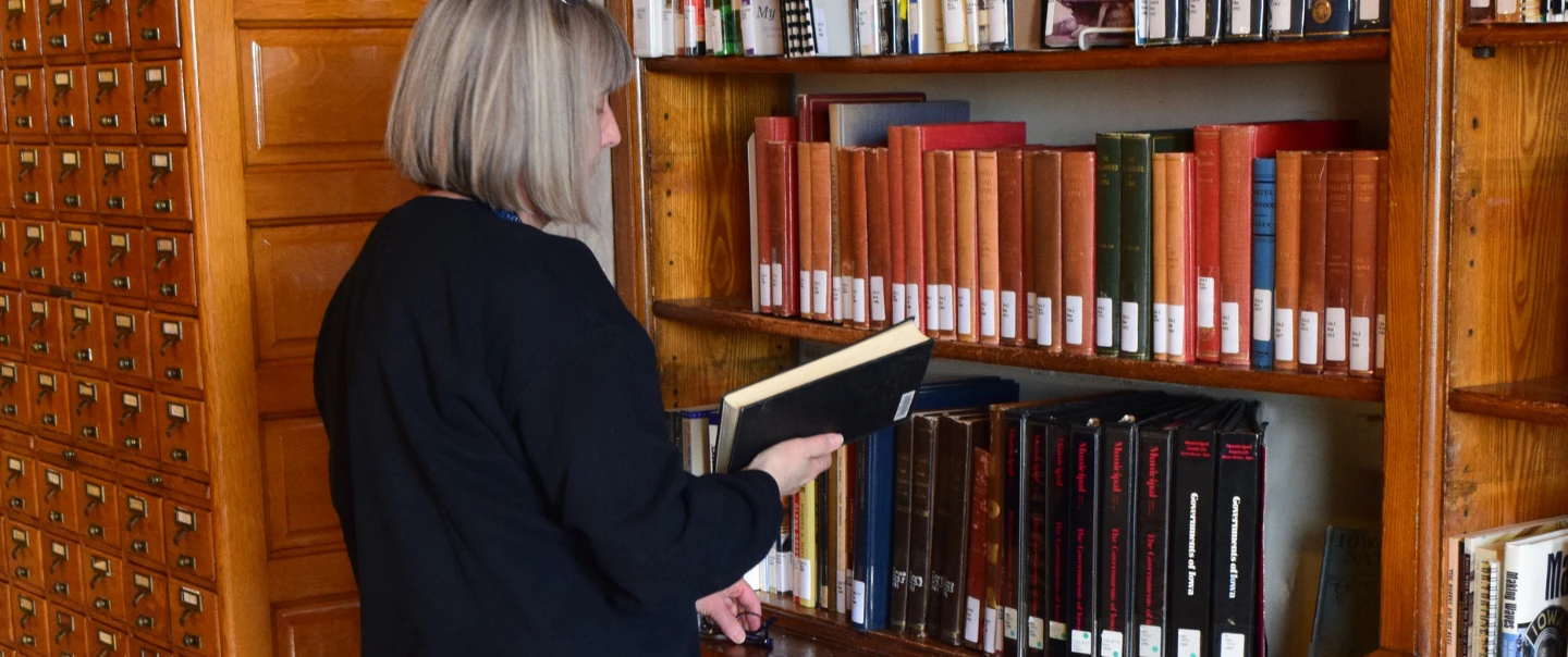 Woman browsing books on the Law Library shelves.