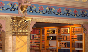 Interior of the Law Library showing the painted stenciling, decorative mouldings, and gilded Corinthian captial at the top of a column.