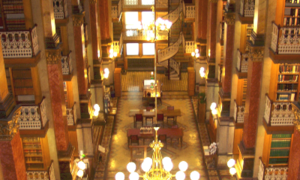 Interior of the Law Library from the top tier looking down the length of the Law Library, a brass chandelier is suspended in the foreground with the glass globes lit.