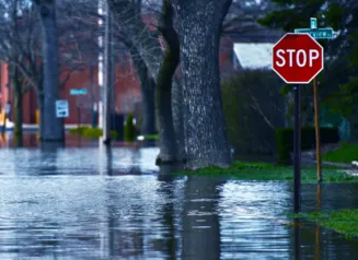Flooded street in a community with a stop sign in the foreground.