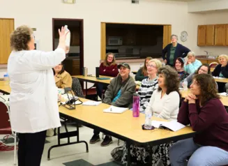 Librarians at a STEM Fair watching a presenter demonstrate a science program.