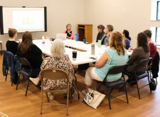 About 15 people sitting around a conference table at the 2024 Director Roundtables at the Prairie City library.