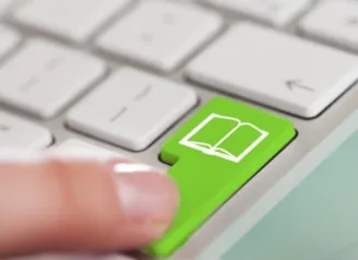 Closeup of a finger pressing a green keyboard button labeled with a book icon.