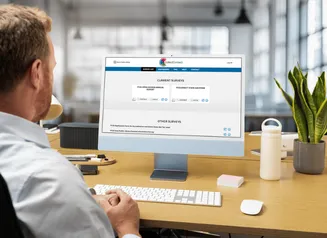 Man sitting in front of a computer open to the Annual Survey interface.
